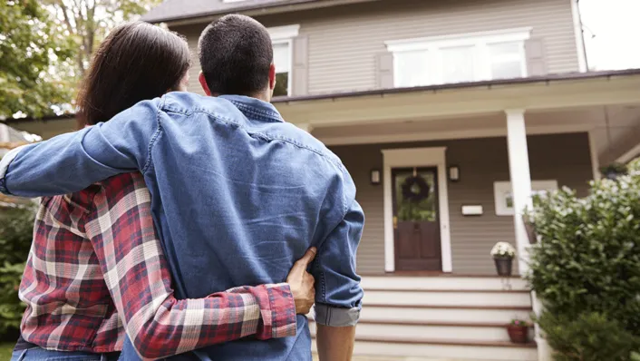 a couple looks at their home from the sidewalk