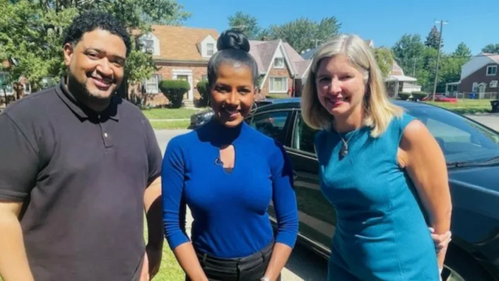 Diverse group of three people smiling outside of residential home