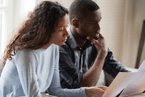 a couple stares at a computer screen, looking worried