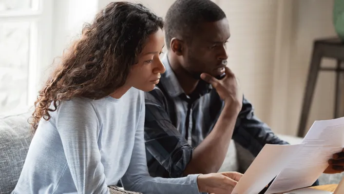 a couple stares at a computer screen, looking worried