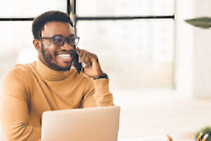 Man on phone in front of laptop computer