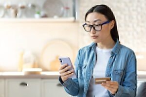 A woman enters her credit card information into a cellphone.