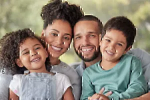 Young African American Couple with Two Young Children on Their Laps Smiling