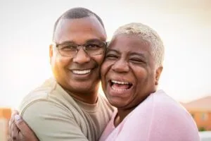 Happy senior couple embracing during sunset outside, facing the camera