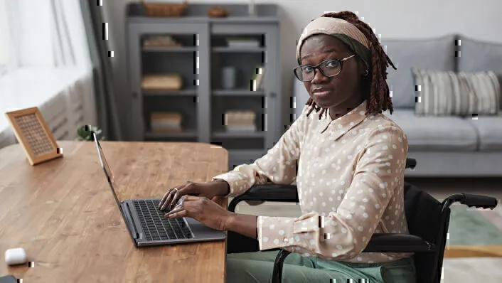 Young African American Woman in Wheelchair Using Laptop at Desk