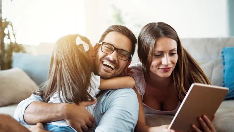 young family embracing on couch with sunglow through window