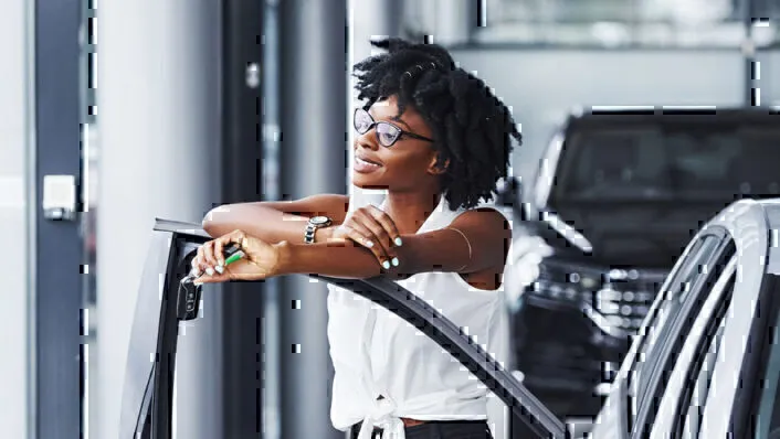 Image of woman with glasses holding car keys, arms crossed over open car door