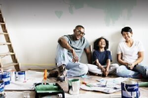 A young family sits on the floor after doing some home renovations.