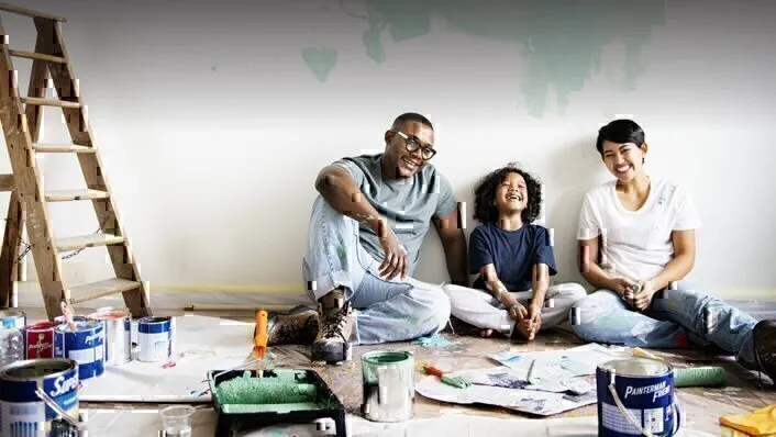 A young family sits on the floor after doing some home renovations.