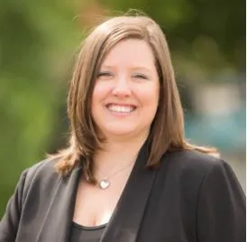 A smiling white woman wearing a black shirt and black blazer