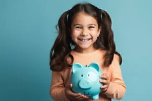 Young girl with pigtails, smiling while holding ceramic piggy bank