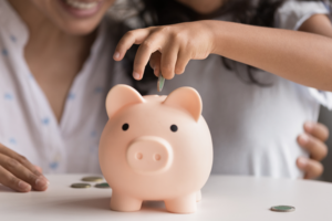 Mom taught daughter to save some money in piggy bank.