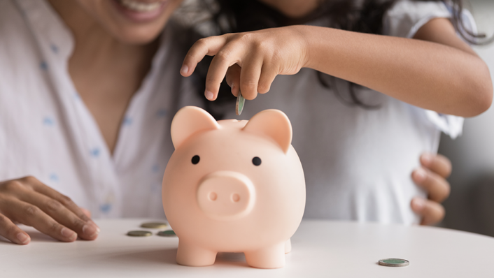 Mom taught daughter to save some money in piggy bank.