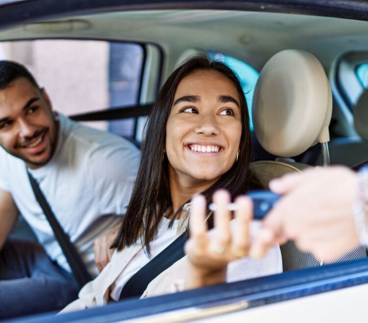 Woman receiving keys while sitting in a car