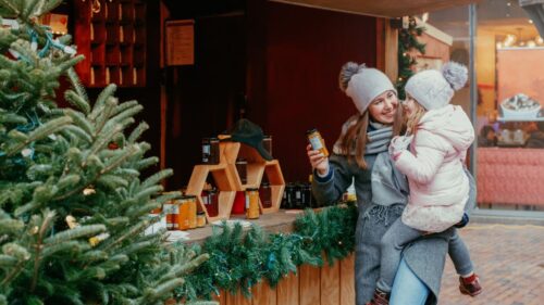 Woman holiday shopping with child in front of store window with christmas tree