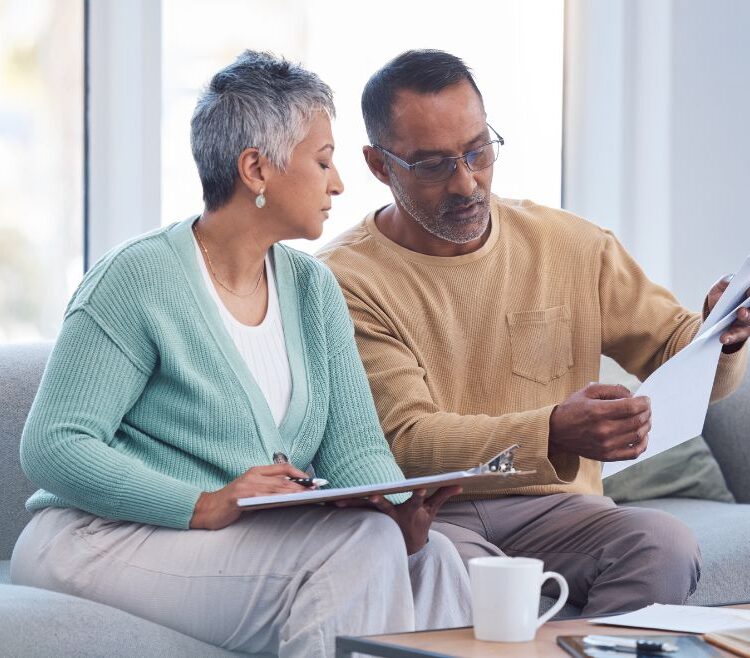 Older diverse couple looking at documents on couch