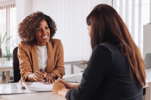 diverse woman sitting at desk with client and documents