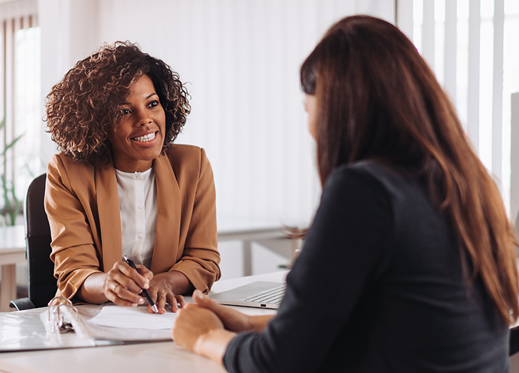 diverse woman sitting at desk with client and documents