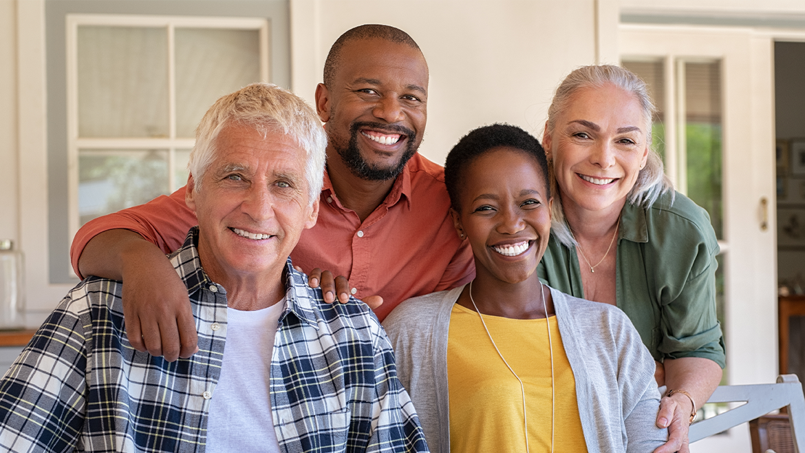 Two senior couples taking a photograph together infront of a house.