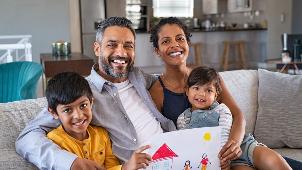 Family of four sitting on light gray couch.