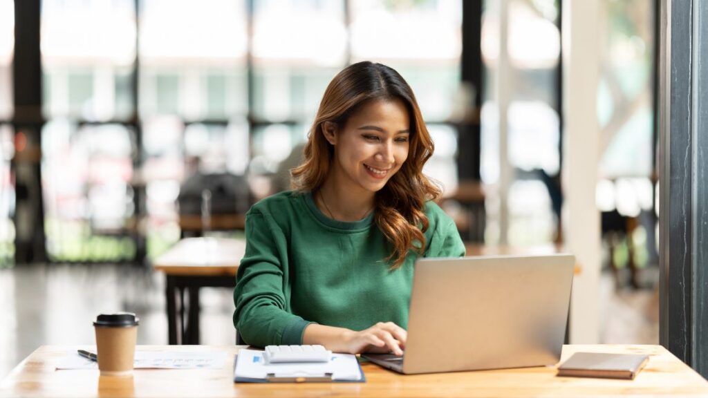 Woman wearing sweater working on laptop.