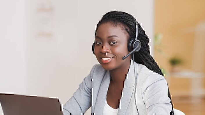 Professional black woman with headset wearing gray blazer.