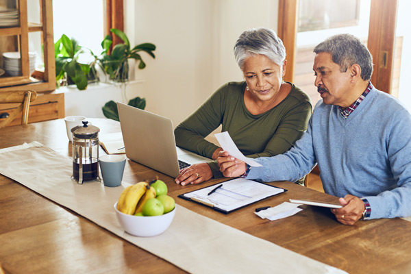 An elderly couple going over finances beside a laptop