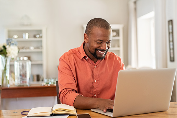 A man in front of a laptop with his checkbook