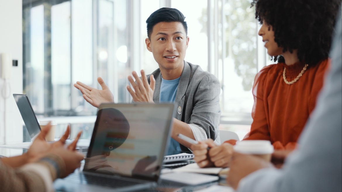 An Asian man in a business meeting talking with other people.