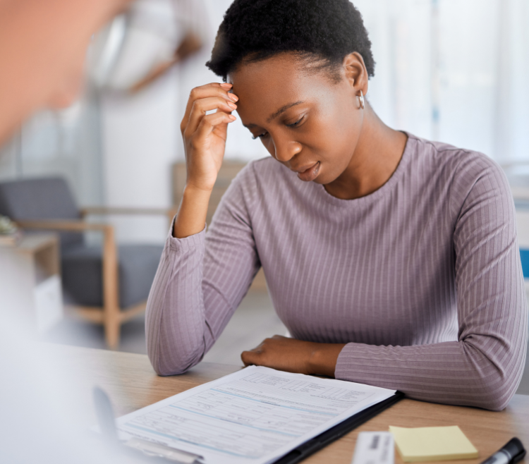 black woman pensively looking at her medical bill