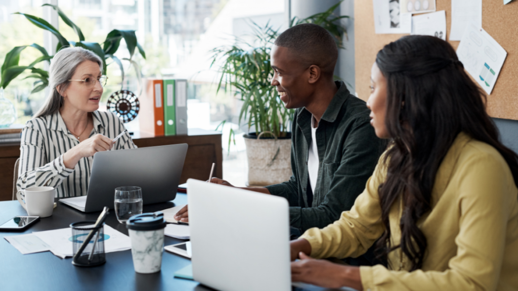 a group of people sitting at a desk talking to each other