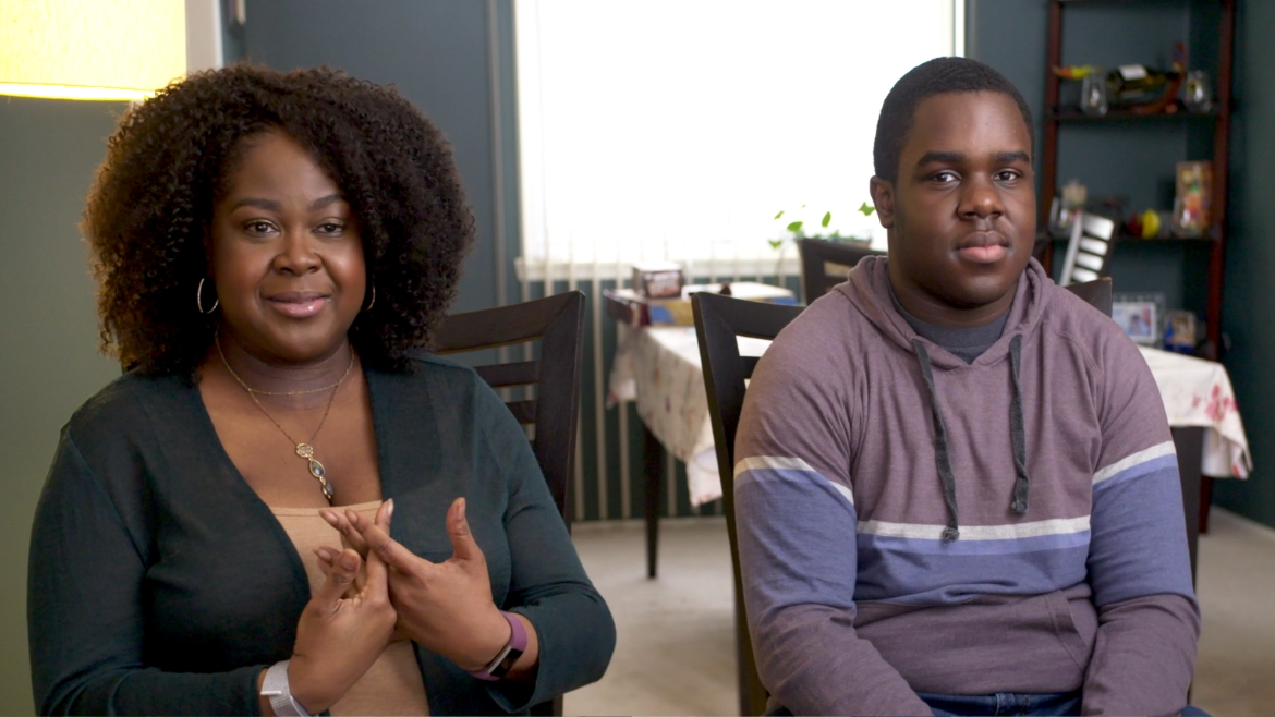 a black woman and her son sitting in their livingroom talking to an interviewer