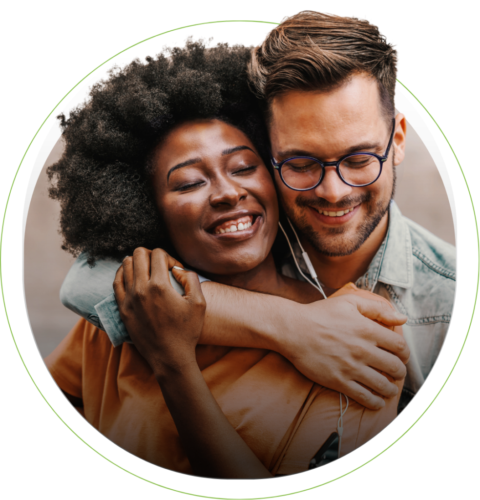 A white man and black woman smiling and embracing.