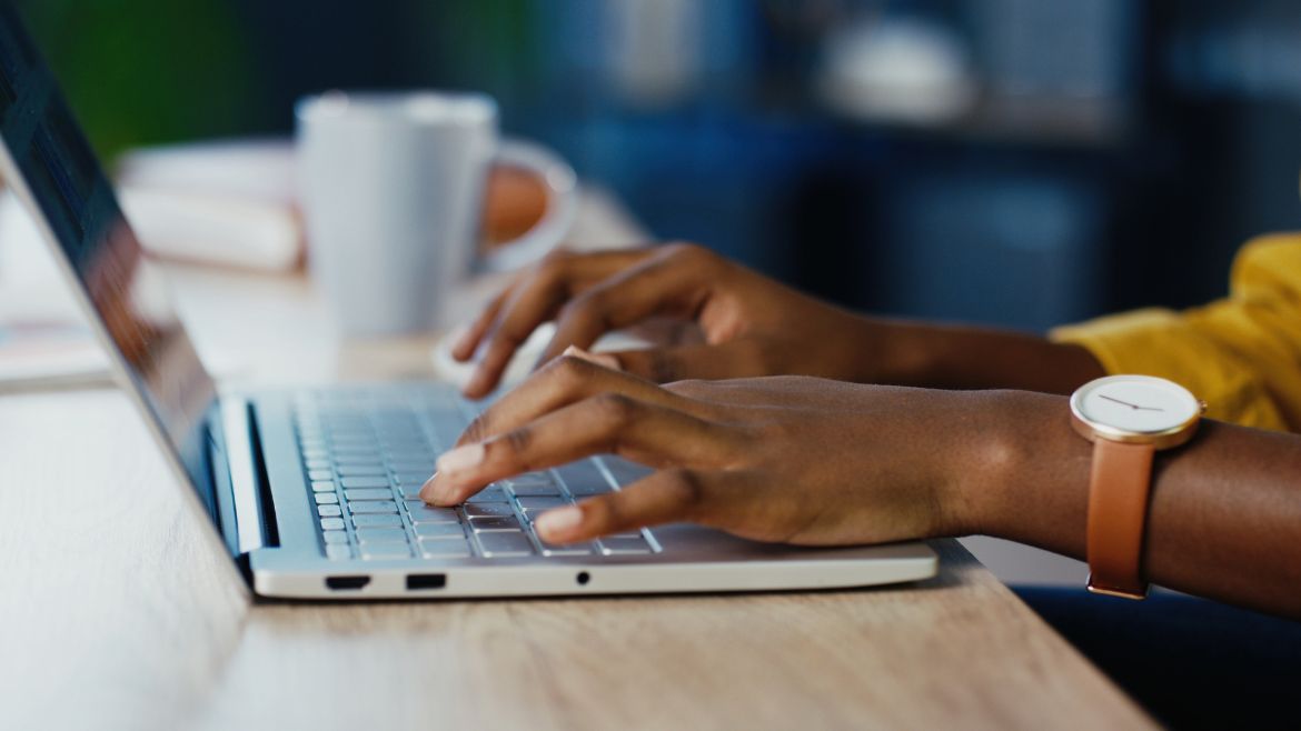 a black woman hands typing away on a computer keyboard