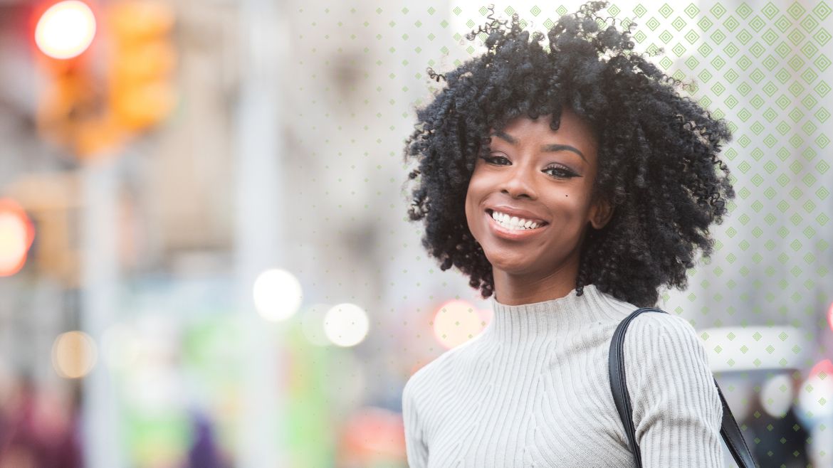 Black woman in grey sweater and short curly hair smiling