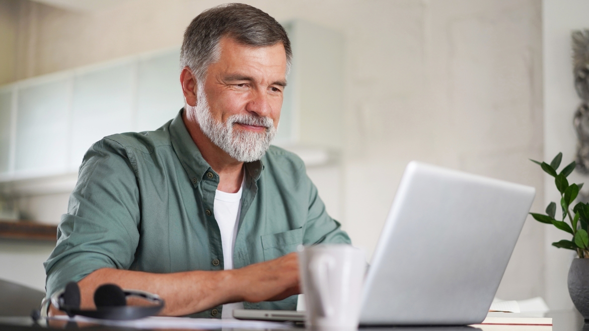 white man with peppered gray hair using a computer in his kitchen